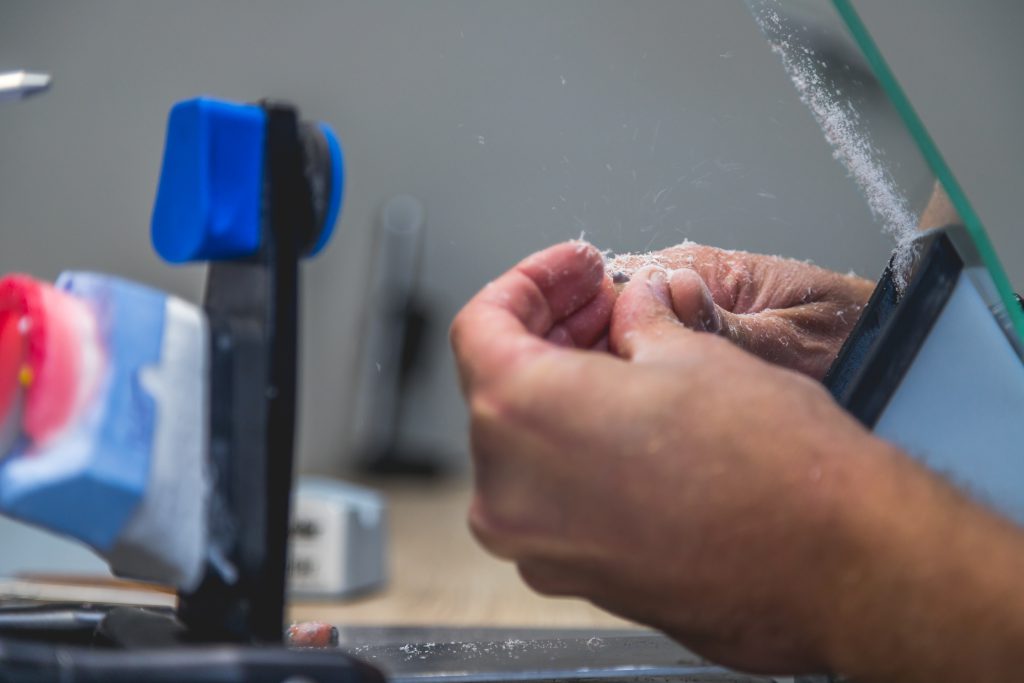 Tandprotheticus werkt met precisie aan gebitsprothese in laboratorium met professionele gereedschappen