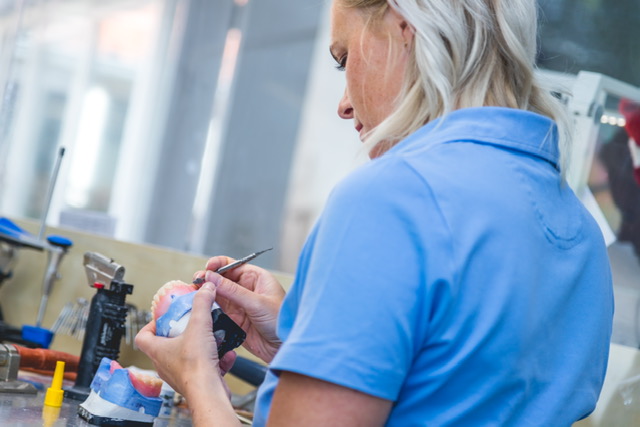 Tandprotheticus werkt aan vervaardiging van kunstgebit in laboratorium met precisie-instrumenten