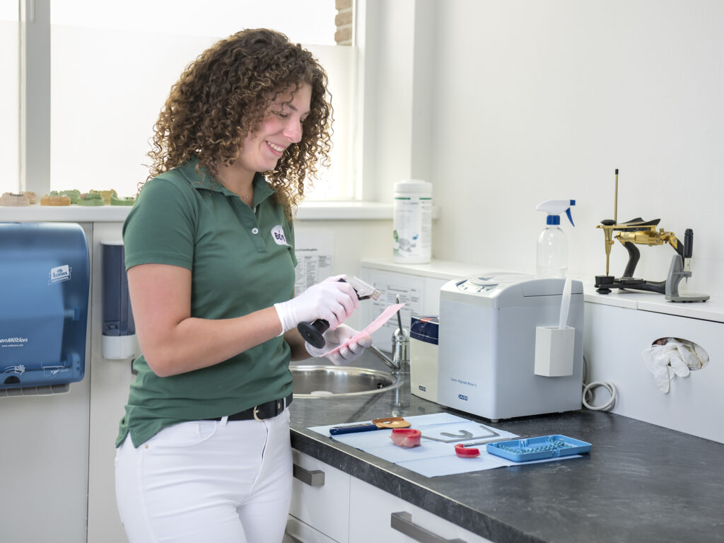 Tandprotheticus werkt aan tandprothese in moderne laboratorium met professionele apparatuur