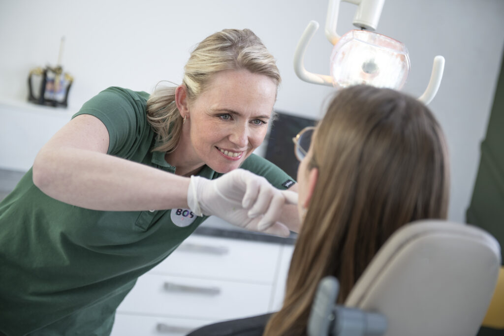 Tandprotheticus in groene kleding behandelt patiënt in moderne tandheelkundige praktijk