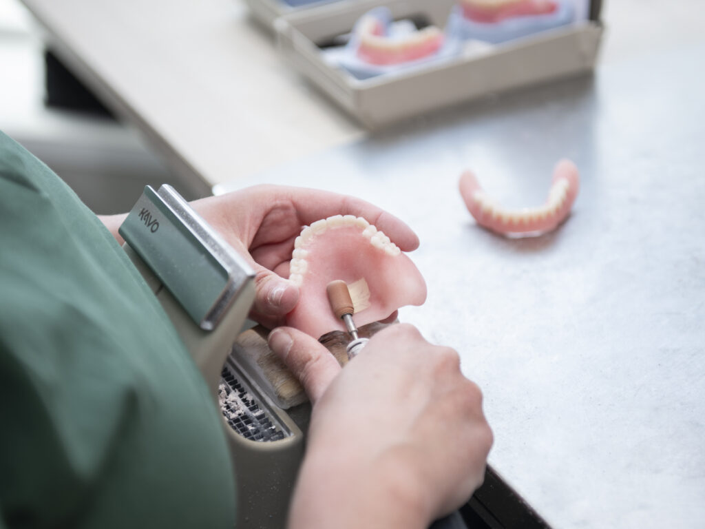 Tandprotheticus werkt aan gebitsprothese met professionele apparatuur in tandprothetische praktijk